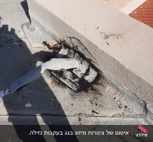 חומר איטום שחור סביב צינור על גג בטון